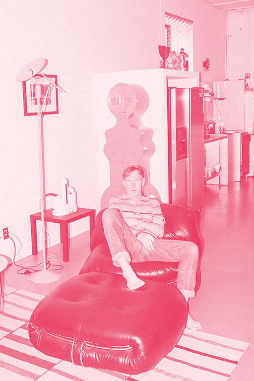 Jim sitting on a chair with his bare foot on top of an ottoman